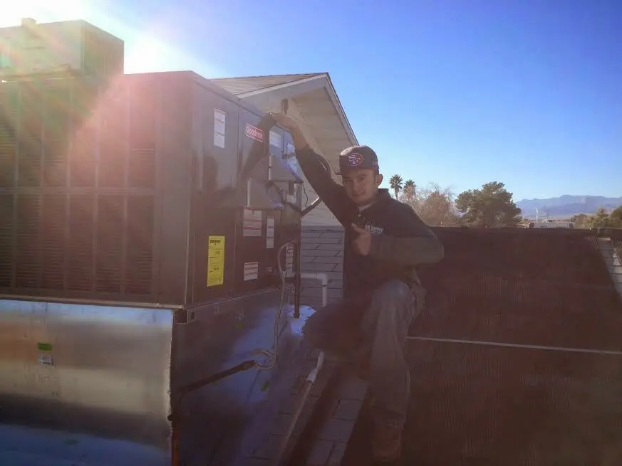 HVAC technician performing Heat Pump Repair on a rooftop unit in Tillamook